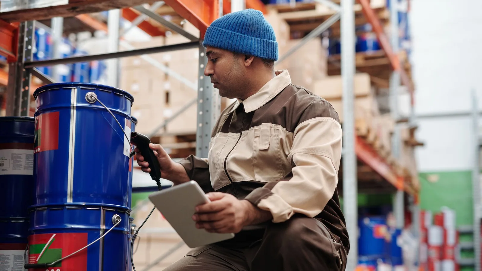 Warehouse worker scanning a barrel with a handheld scanner while holding a tablet